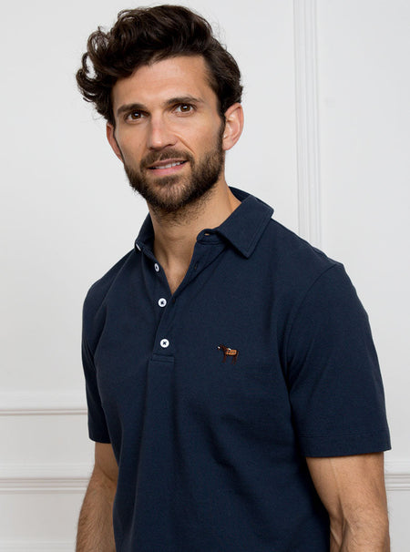 Man wearing navy blue polo shirt in 100% cotton with Newmarket 875 horse logo embroidered on the front.